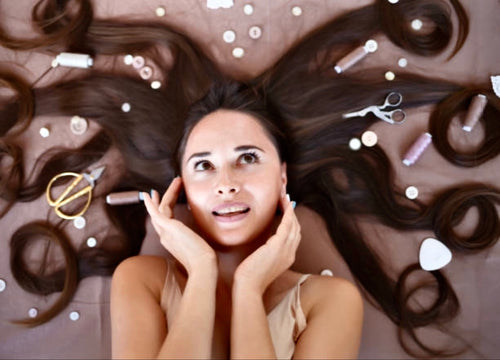 Female model holding her ears laying on the floor, smiling at the camera, photo shoot. Female hair model.