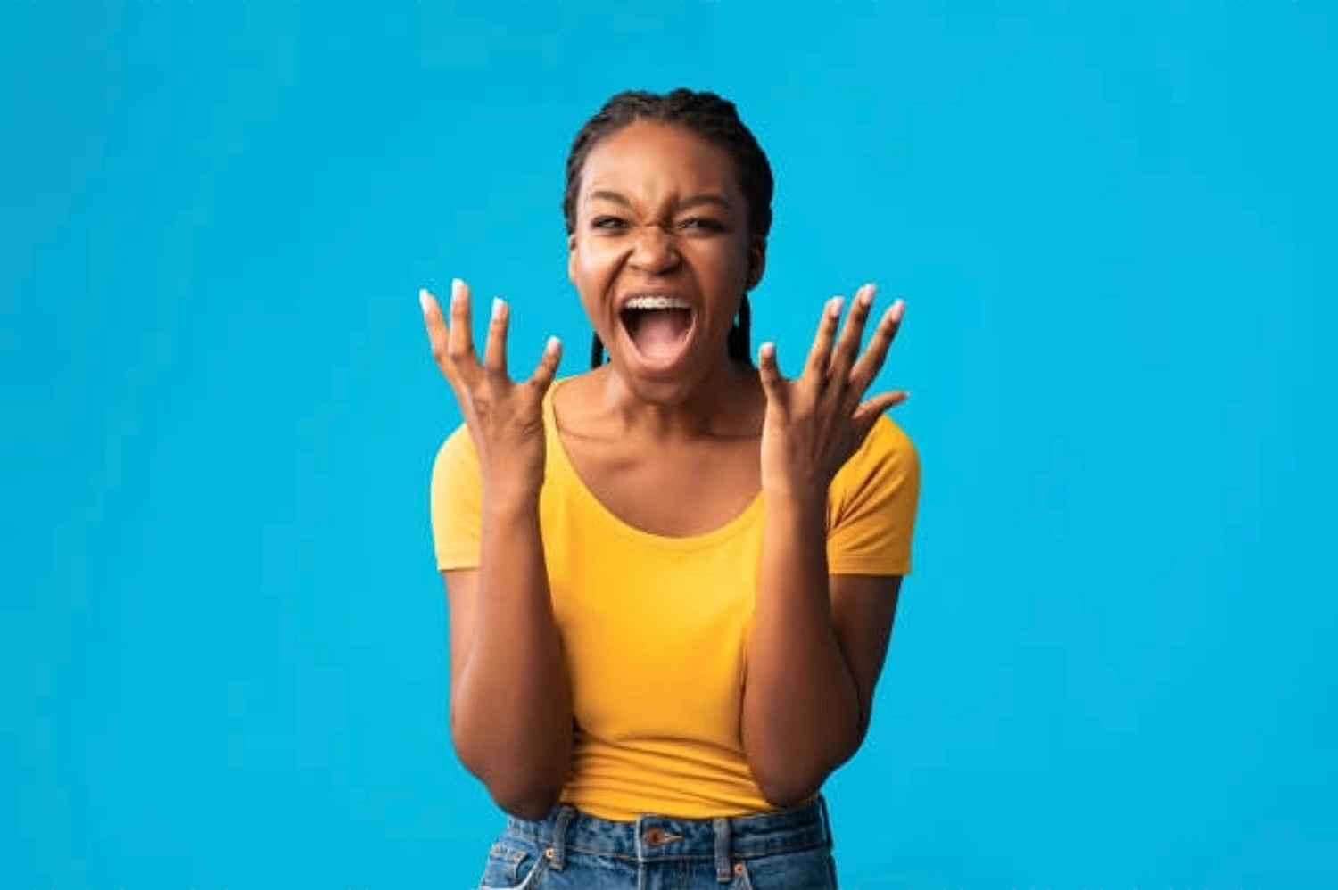 Excited female gesturing both hands in the air open palms wearing yellow T-shirt denim blue jeans