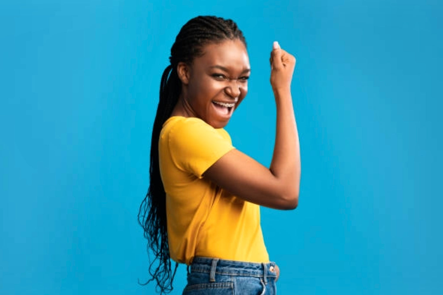 Excited female doing a fist pump wearing yellow T-shirt denim blue jeans